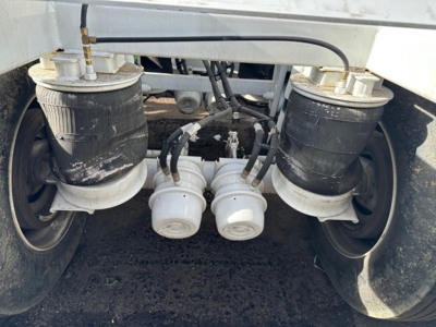 Bottom dump trailer air ride suspension tanks and dual hose connectors with air lines and fittings visible under trailer.