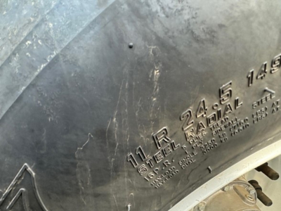 Trailer side showing stamped markings: '11 R 24.5 16 PR STEEL RAIL 1490' and other specs on steel surface; part of CPS Air Ride Bottom Dump trailer.