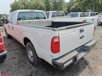 Ford F-250 Super Duty crew cab pickup truck with extended bed and open tailgate, white exterior, short bed, visible rear taillights and bumper in a parking lot.