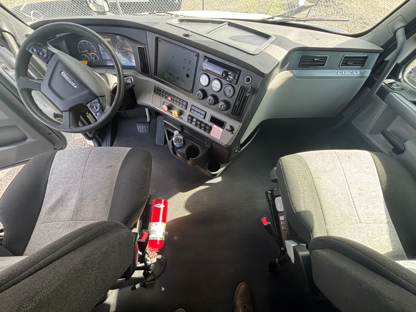 Freightliner CA-126 truck cab interior showing steering wheel, dashboard with multiple gauges and controls, driver and passenger seats, center console, and gear shifter.