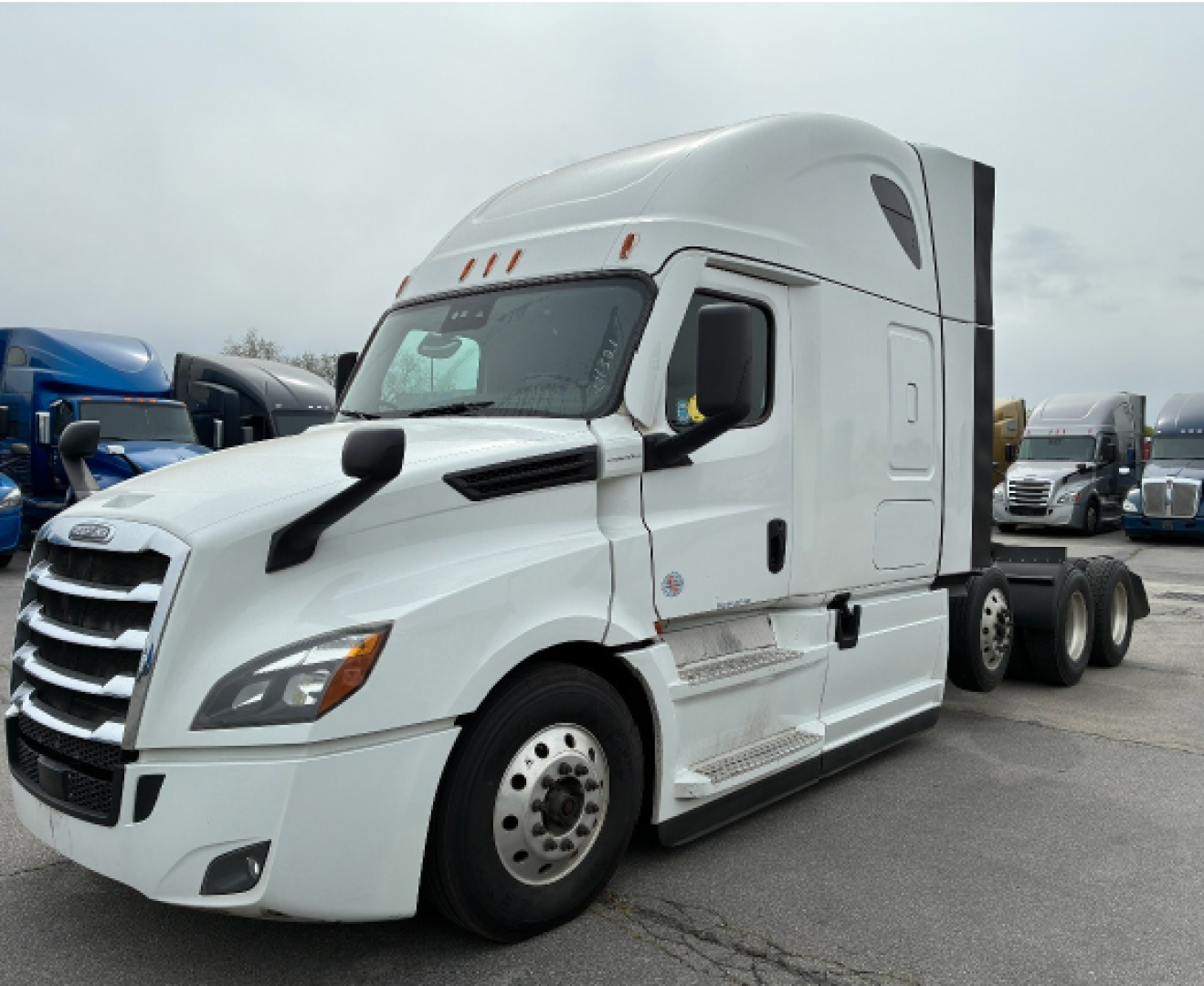 Truck cab and front of 2021 Freightliner CA-126 conventional sleeper tractor in white, with multiple axles and chrome steps.