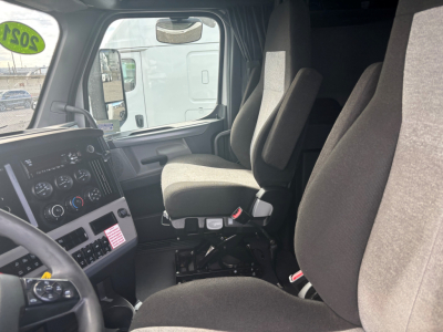 Trucking cab interior of a Freightliner CA-126 with driver and passenger seats, dashboard gauges, steering wheel, and a view through the left door window.