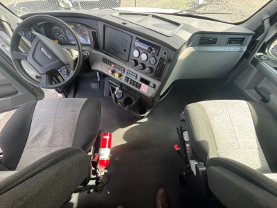 Freightliner CA-126 truck cab interior showing steering wheel, dashboard with multiple gauges and controls, driver and passenger seats, center console, and gear shifter.
