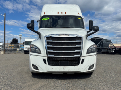 Front view of a white Freightliner CA-126 sleeper cab truck showing grille, bumper, and headlights with a green 2021 sticker on the windshield.