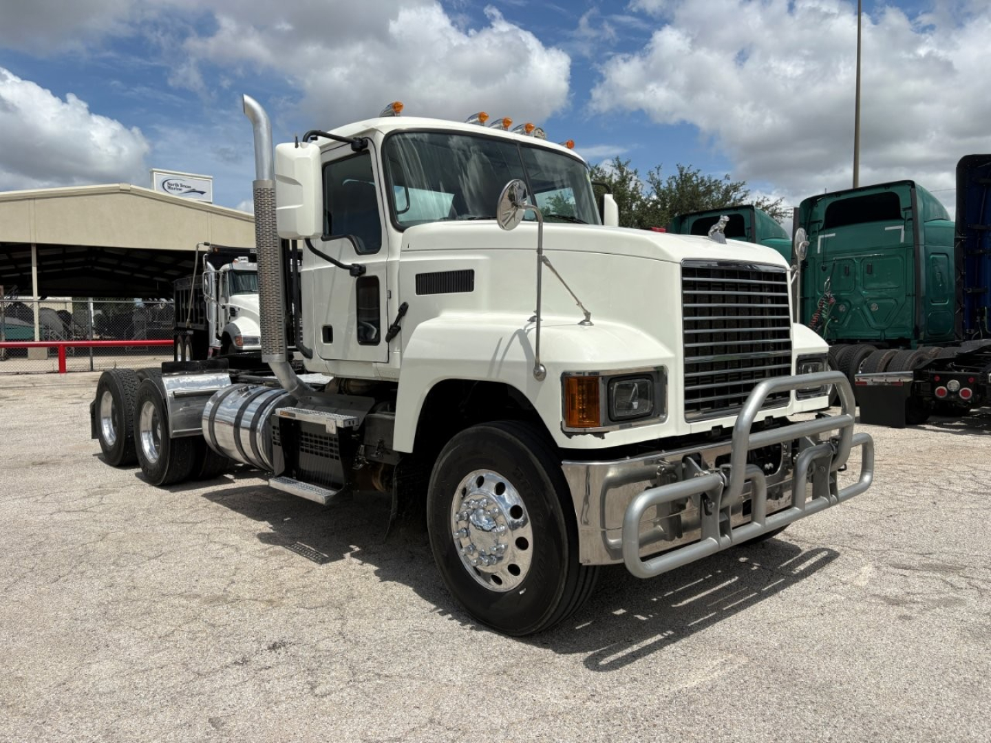 Mack PI64T conventional daycab truck side/front view showing chrome bumper guard and dual fuel tanks.