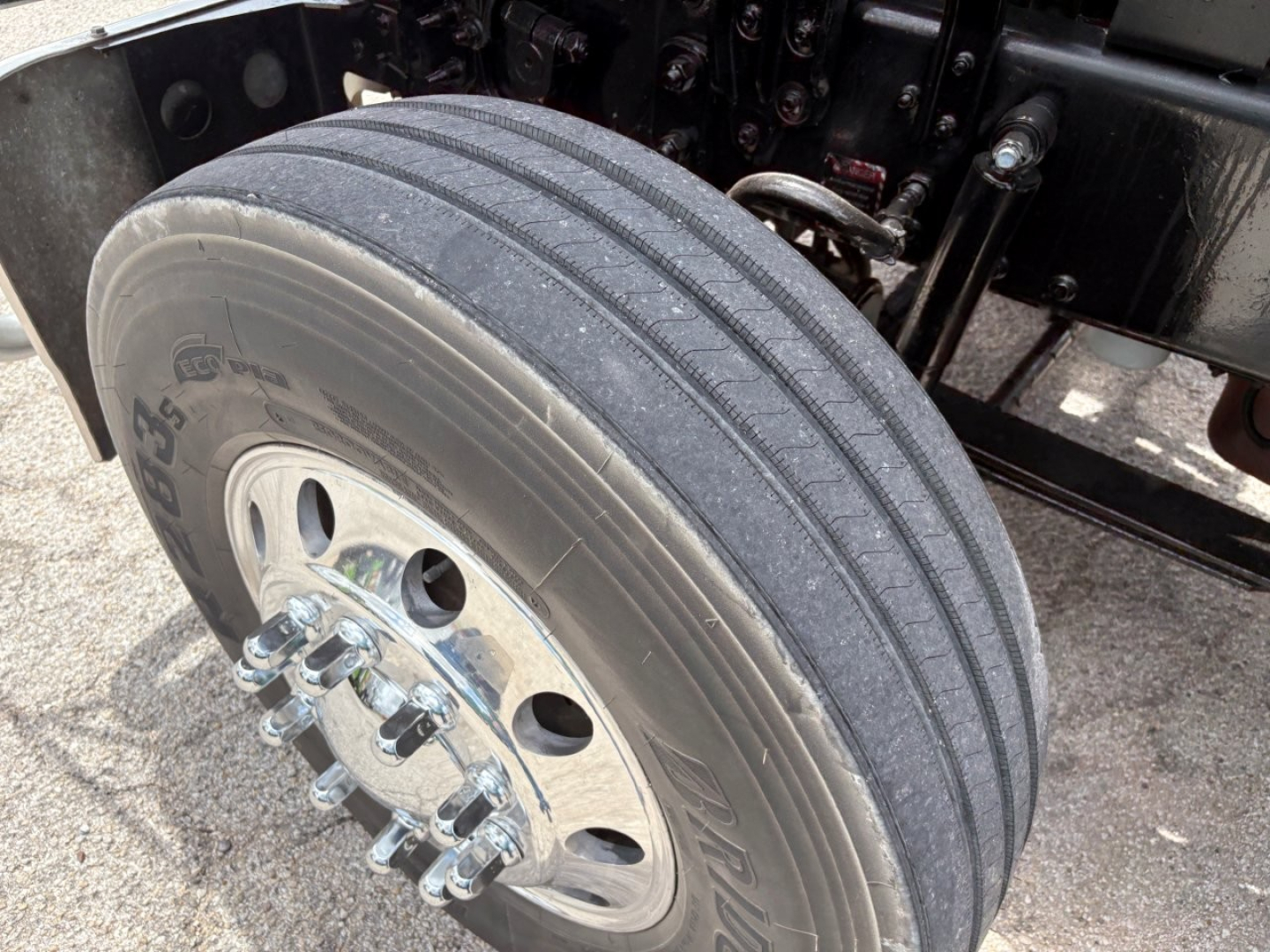 Truck wheel and front suspension of a 2020 Mack PI64T showing a single dual-tire setup with chrome lug nuts and Bridgestone tire markings.