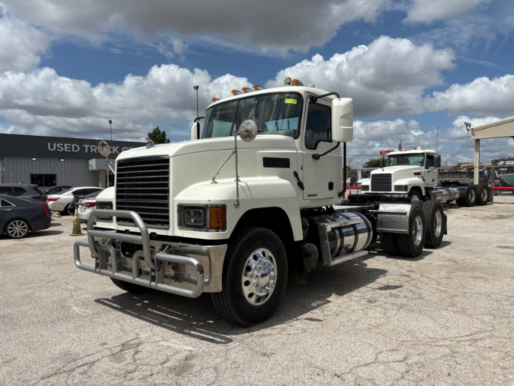 Mack PI64T truck in a dealership lot showing front and side view with bumper guard and dual rear axles.