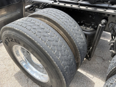 Mack PI64T truck rear dual tires with tread and wheel visible, undercarriage and suspension components partially visible.
