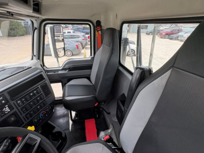 Truck cab interior showing driver seat, passenger seat, dashboard with controls, steering wheel, and window views.
