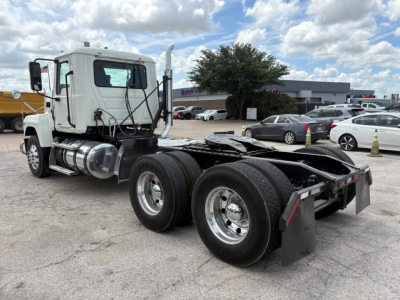 Truck chassis and cab of a 2020 Mack PI64T daycab with twin rear axles and sleeperless cab, side mirror, fuel tanks, and visible VIN sticker.