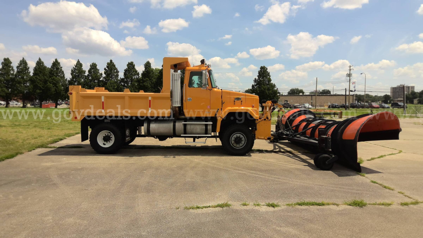 Volvo Autocar 1997 plow truck with large orange snow plow attachment on the front, side view showing cab and chassis