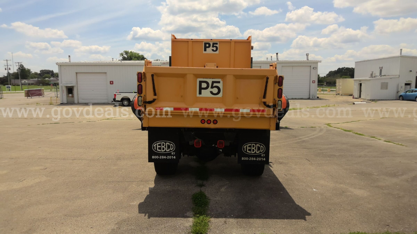 Rear view of a yellow Volvo Autocar plow truck with P5 marking, showing taillights, mudflaps, and welders, in a lot.