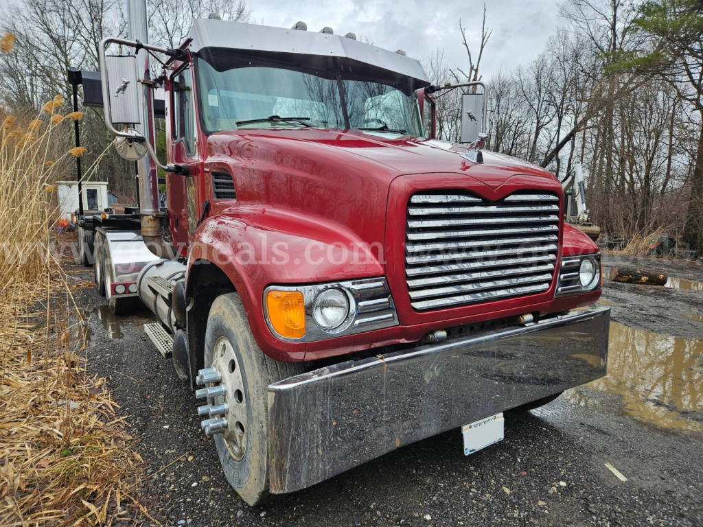 Front view of a red 2003 Mack CV713 Granite truck showing chrome grille, large bumper, dual headlights, and heavy-duty tires.