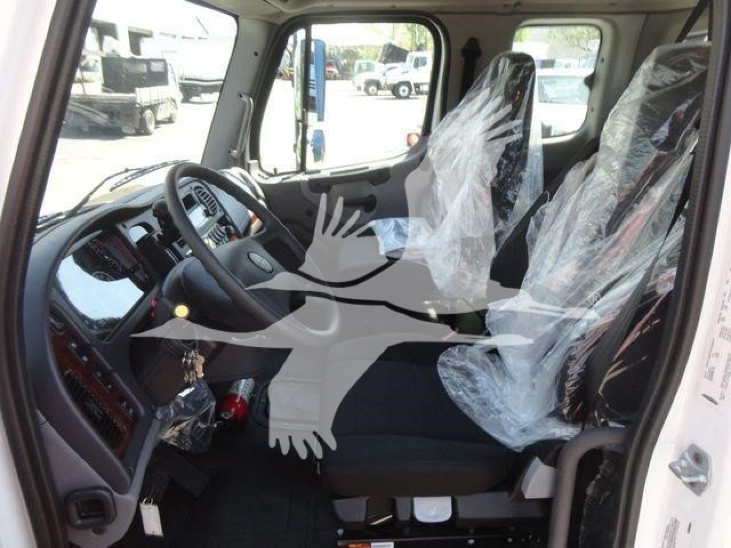 Cab interior of a 2027 Freightliner M2 106 with plastic-covered seats, front row including steering wheel and dashboard, stock image of new rollback truck.