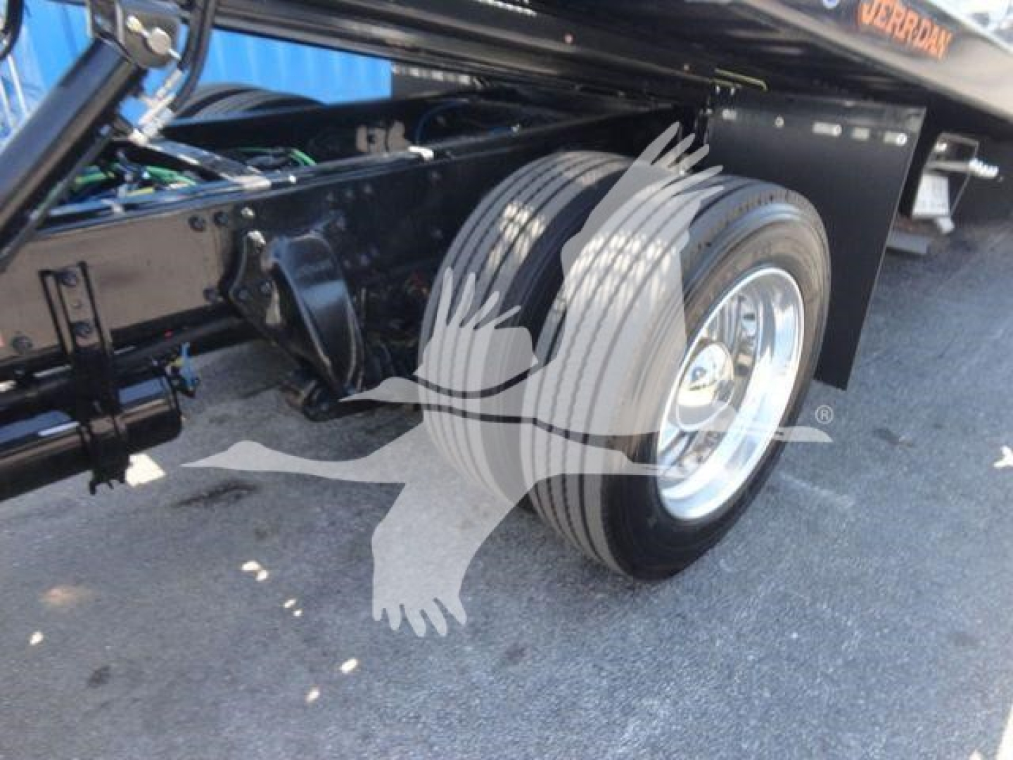 Freightliner M2 106 chassis with front dual tires and suspension components visible; wheel and tire detail with black frame and hydraulic components in view.