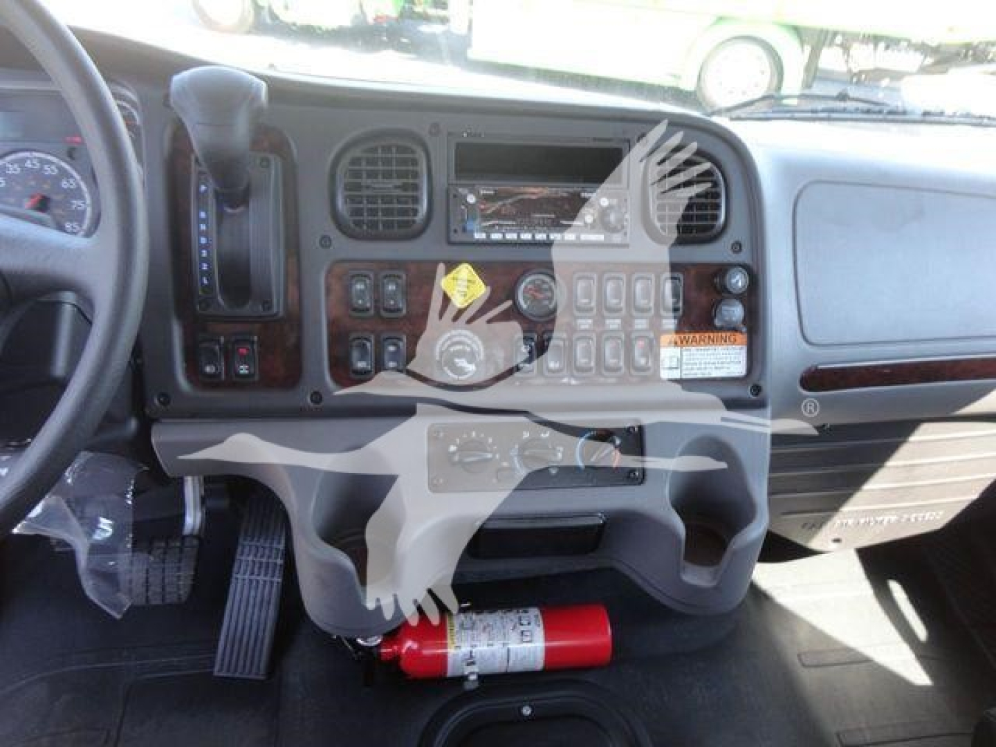 Freightliner M2 106 dash area showing controls and a red fire extinguisher under the dashboard.