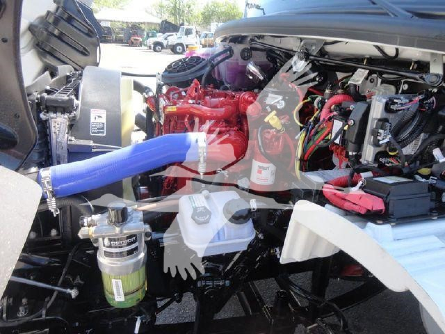 Cab interior of a Freightliner truck engine bay with red engine, blue hose, multiple electrical harnesses, and white windshield wiper area.