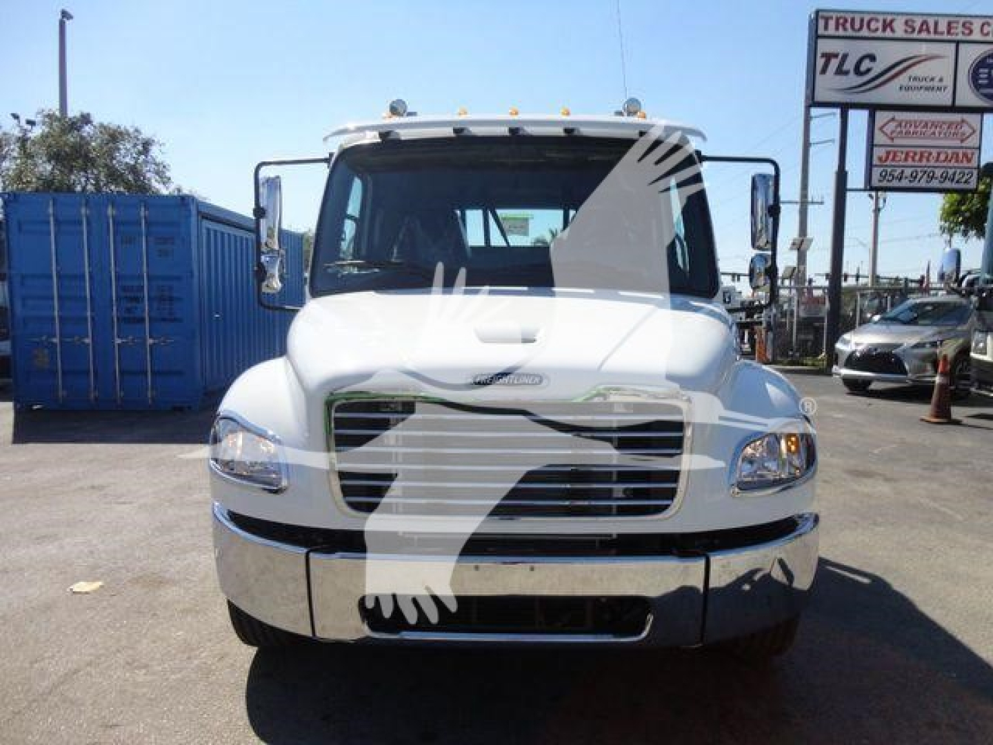 Freightliner M2 106 rollback truck front view with white cab and chrome bumper, stock image with dealership lot in background