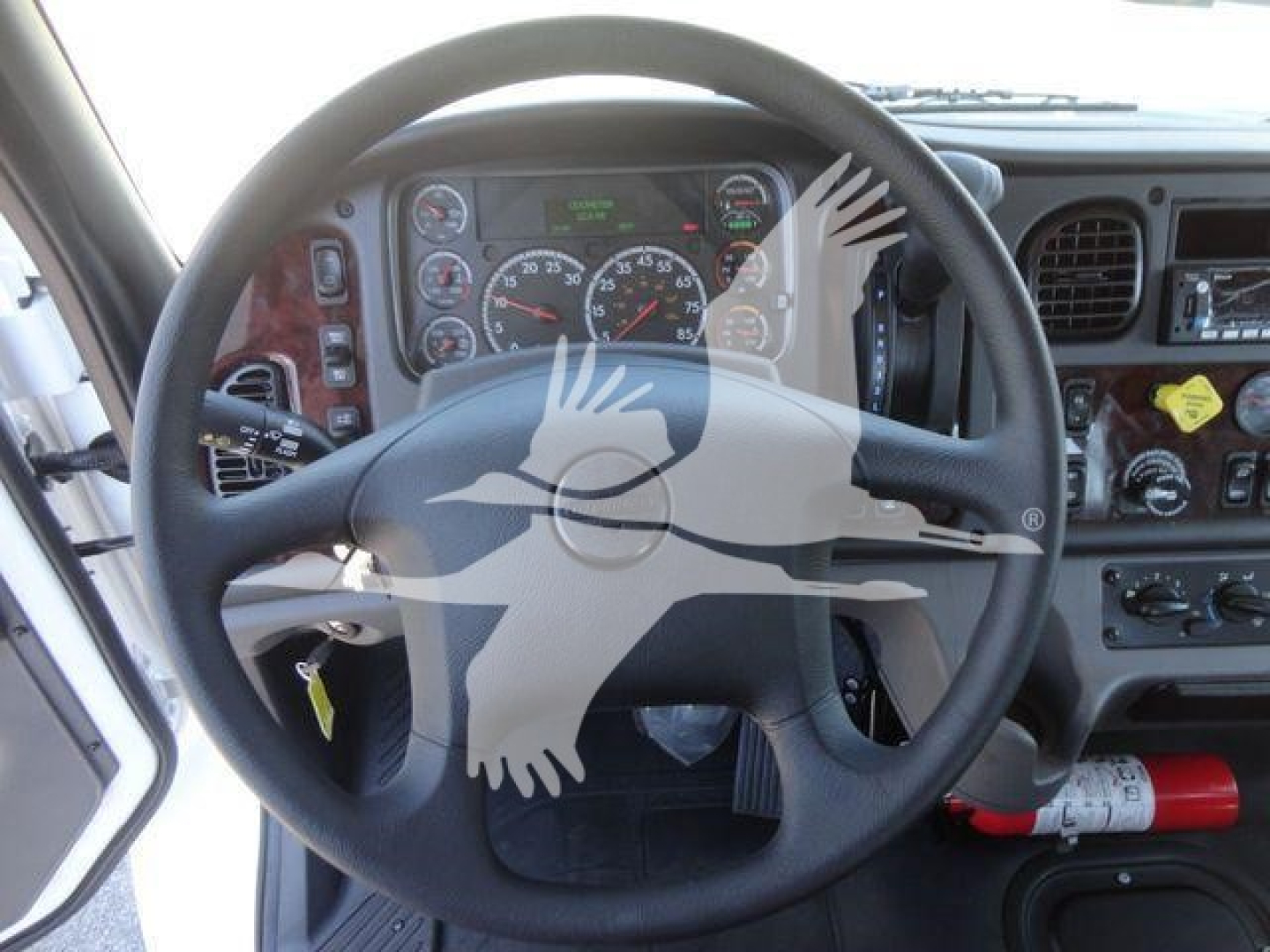 Dashboard and steering wheel view of a Freightliner M2 106 cab interior with gauges, steering wheel, and controls visible.