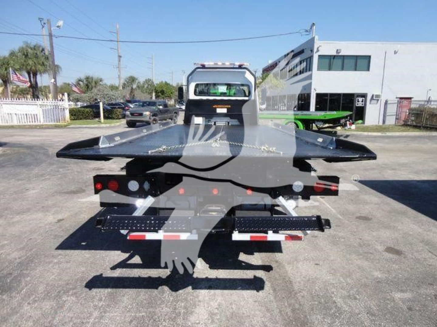 Freightliner M2 106 rollback truck back view showing flatbed and dovetail, chrome bumper, taillights, and towing equipment.