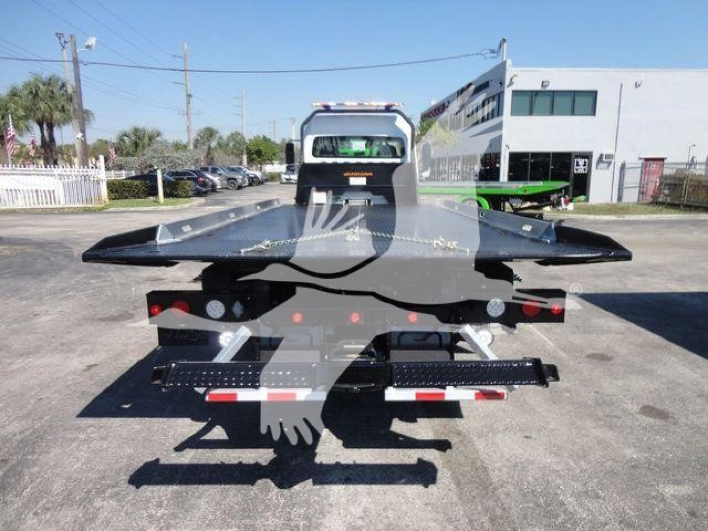 Flatbed rollback bed of a Freightliner M2 106 chassis showing a heavy-duty tow hitch and rear lighting.