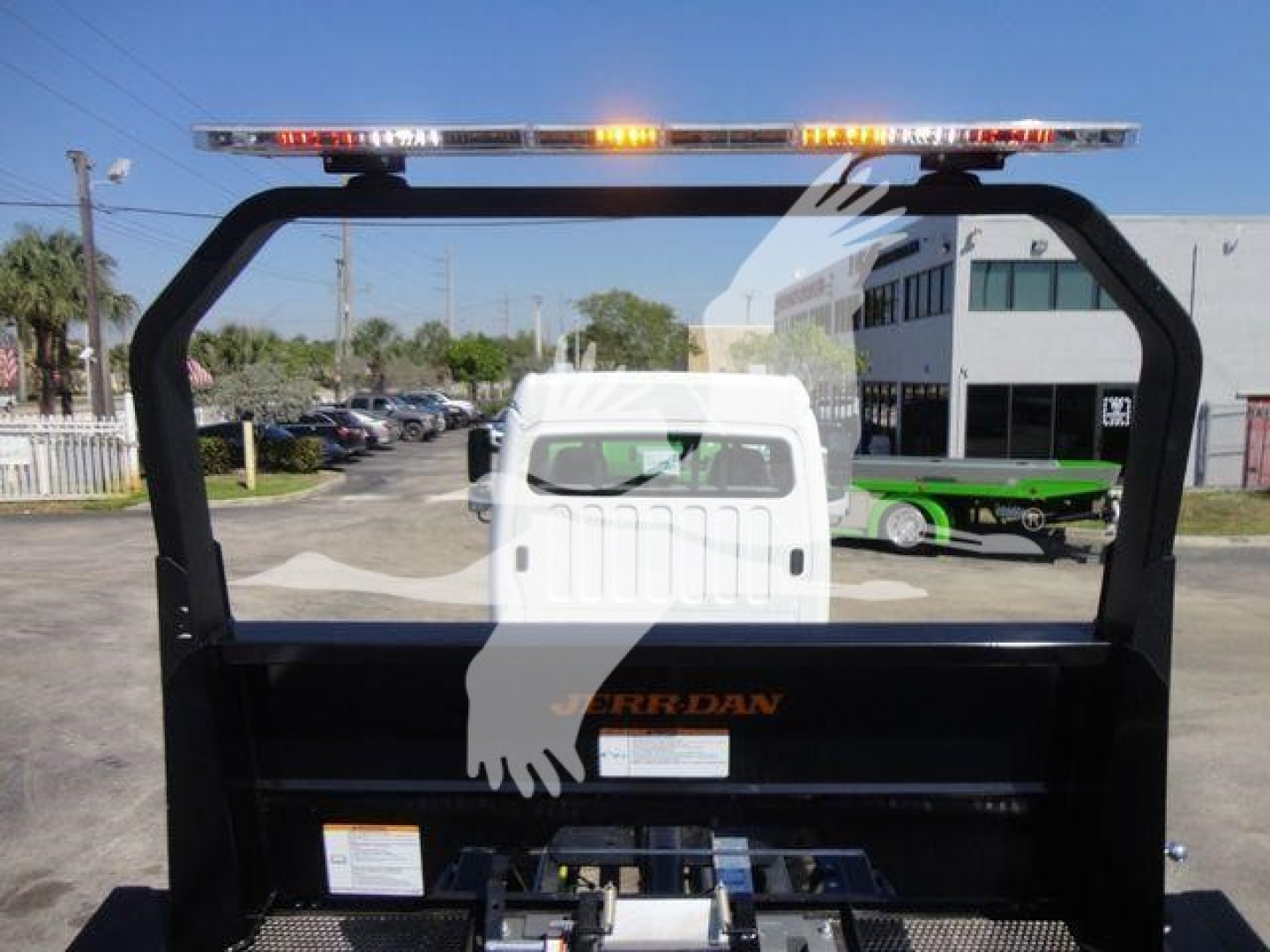 Truck bed of a 2027 Freightliner M2 106 rollback showing a cab-back setup and a light bar on top; partial branding text 'BERRY DAN' or similar on the bed side; no legible serials.