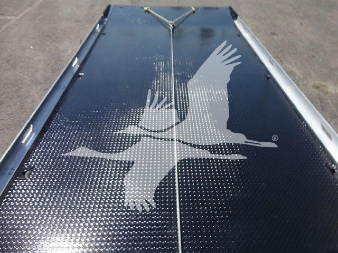 Truck bed platform showing textured steel surface with a white bird silhouette decal and forklift hooks along edges.