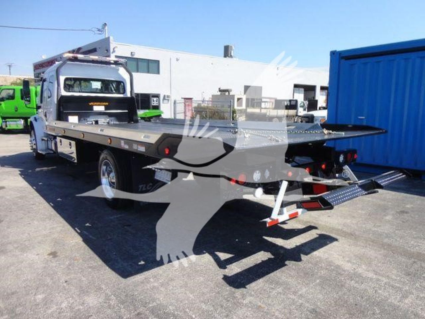 Freightliner M2 106 rollback bed truck with flatbed and ramps, side view showing rear and wheel layout.