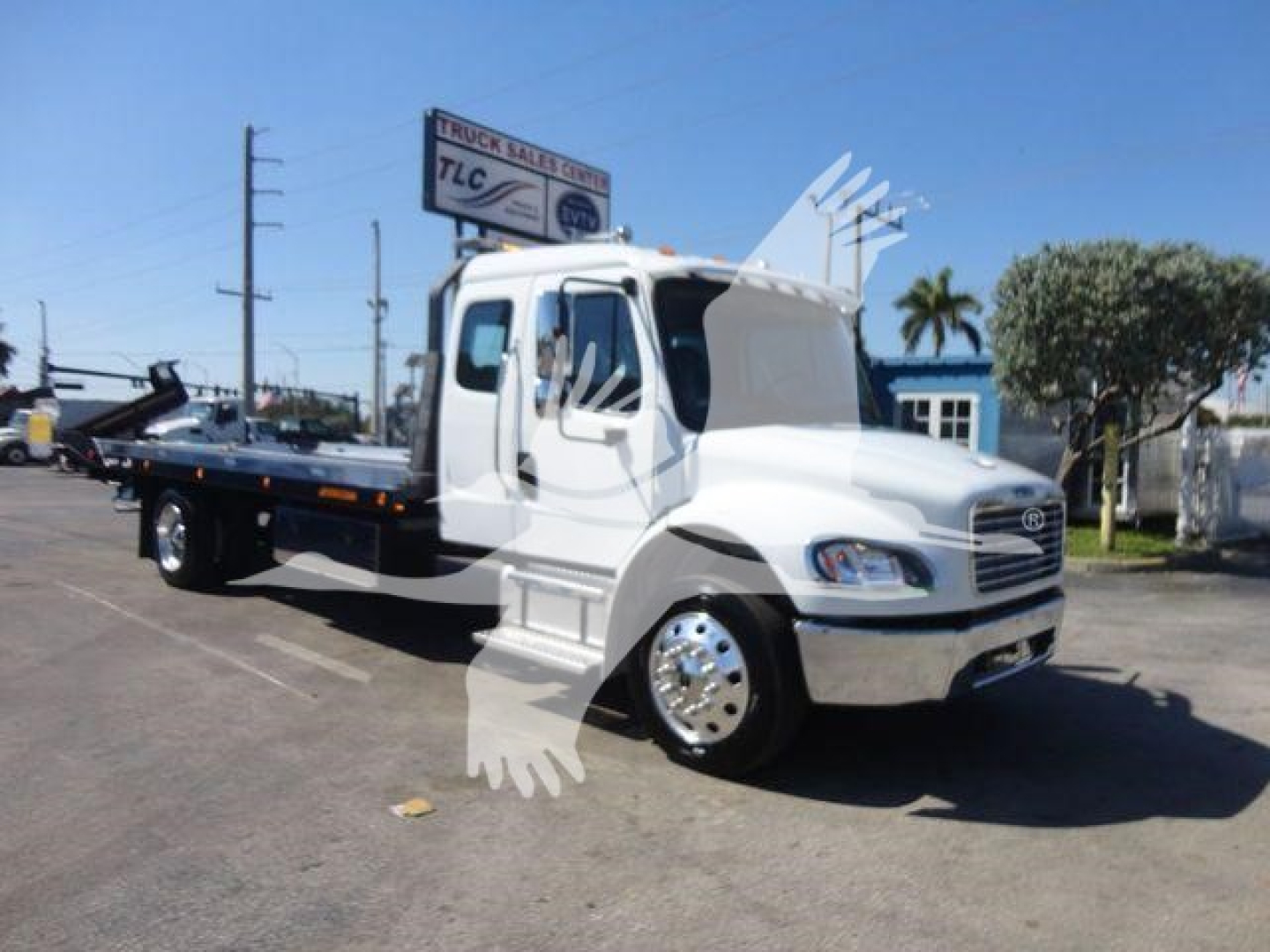 Freightliner M2 106 rollback tow truck side view showing flatbed, cab, and chrome wheels.