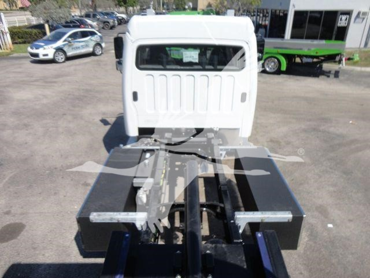 Truck cab rear view showing flatbed chassis with heavy-duty toolboxes on each side and mount points for a rollback crane, white cab, black equipment boxes.