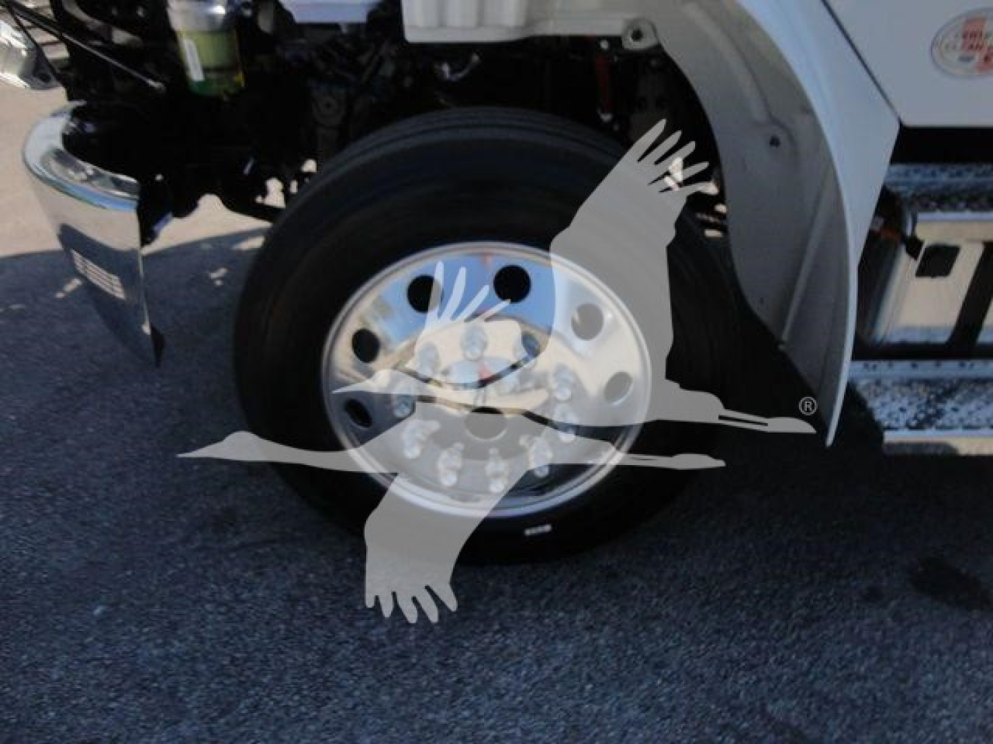 Truck wheel and front fender area of a 2027 Freightliner M2 106 rollback truck showing front tire, wheel, and bumper.