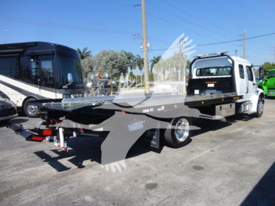Flatbed rollback tow truck in white and gray with hydraulic platform, rear hitch, and front cab visible, side view showing wheels and control console.