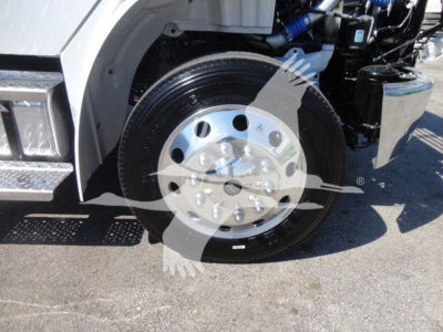 Freightliner M2 106 front wheel and engine bay visible showing chrome wheel hub and part of cab; rollback truck with mechanical components