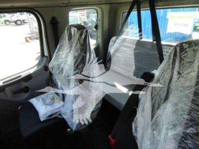 Cabin interior of a Freightliner M2 106 rollback showing front and rear seating wrapped in plastic and protective covers.