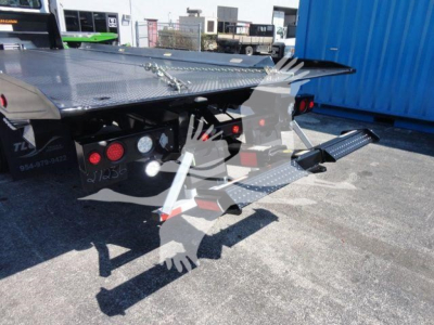 Freightliner M2 106 rollback truck bed with spoke-steel diamond plate surface, rear hydraulic platform steps, and taillights visible.