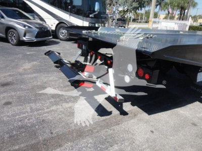 Freightliner M2 106 rollback truck bed with hydraulic loading ramps and warning lights visible.