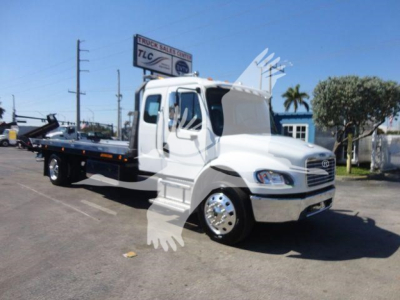 Freightliner M2 106 rollback tow truck side view showing flatbed, cab, and chrome wheels.