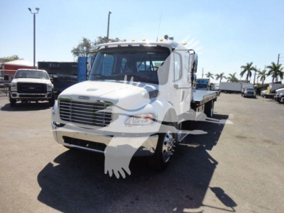 Freightliner M2 106 rollback truck front-left view showing cab, grille, headlights, and flatbed/roll-back chassis.