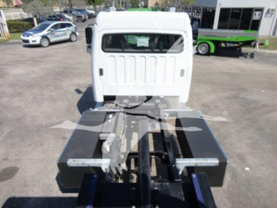 Truck cab rear view showing flatbed chassis with heavy-duty toolboxes on each side and mount points for a rollback crane, white cab, black equipment boxes.
