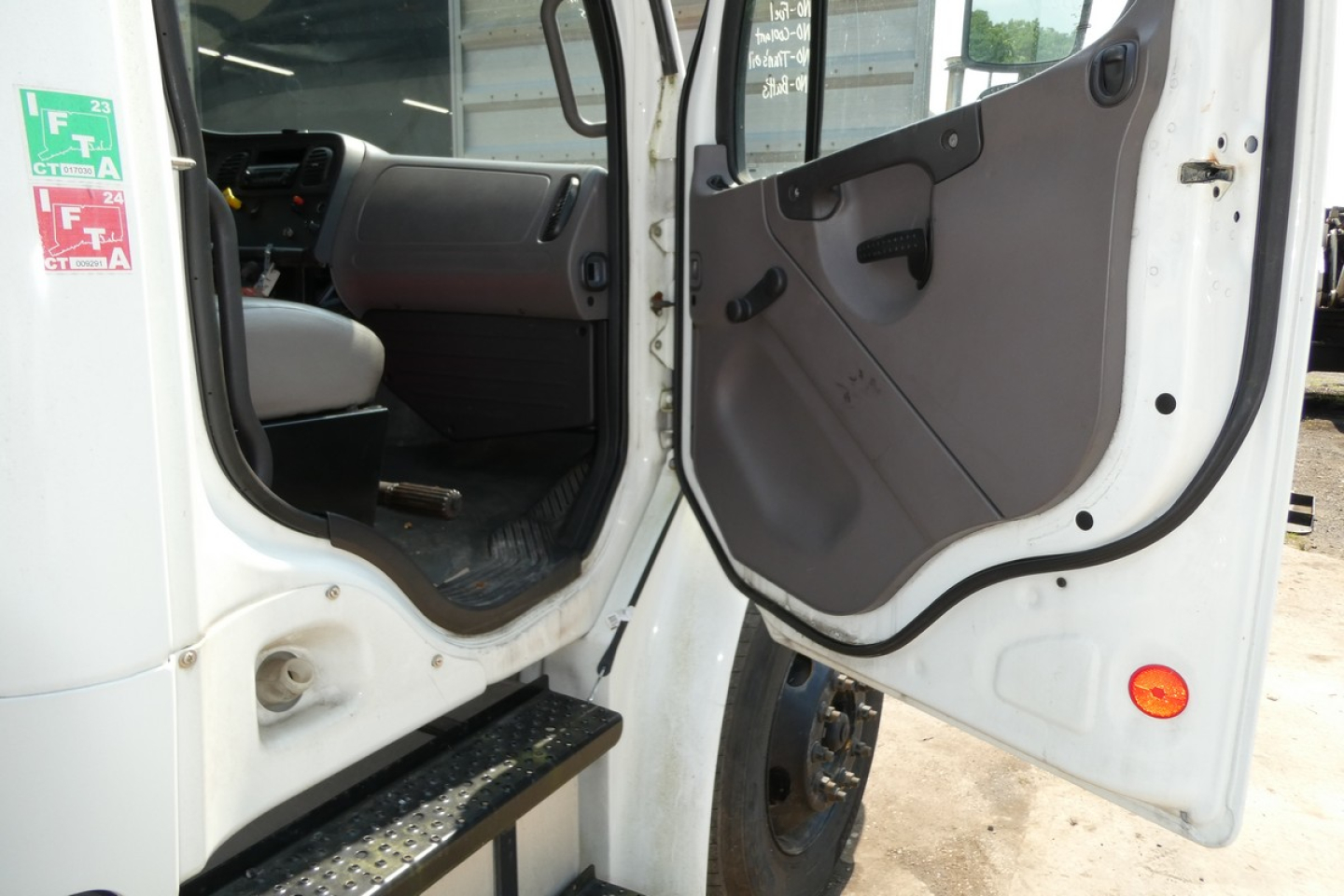 Truck cab entry door open showing interior of Freightliner M2-106 cabin and entry step