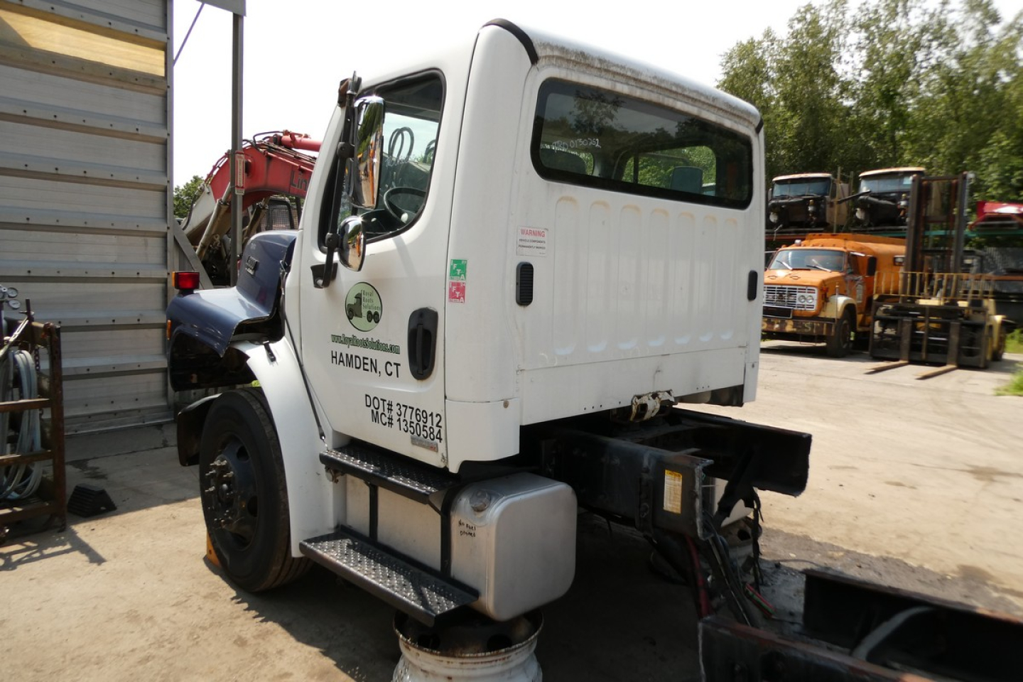 White Freightliner M2-106 truck cab side view showing fleet decals and service stickers