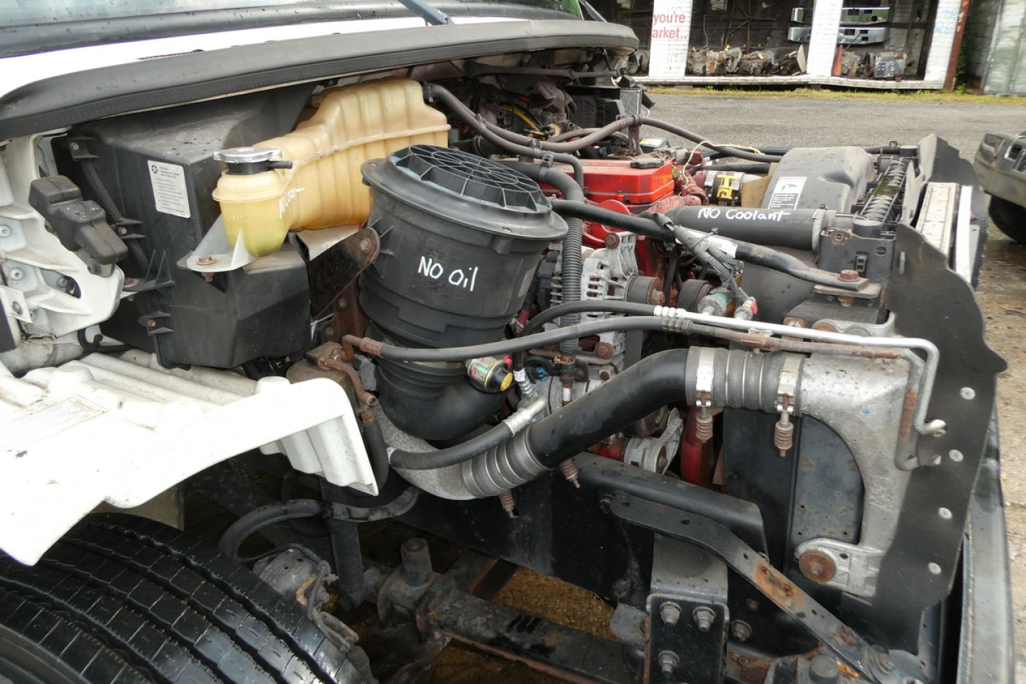 Freightliner M2-106 engine bay showing air filter housing, coolant reservoir, and assorted hoses and metal brackets.