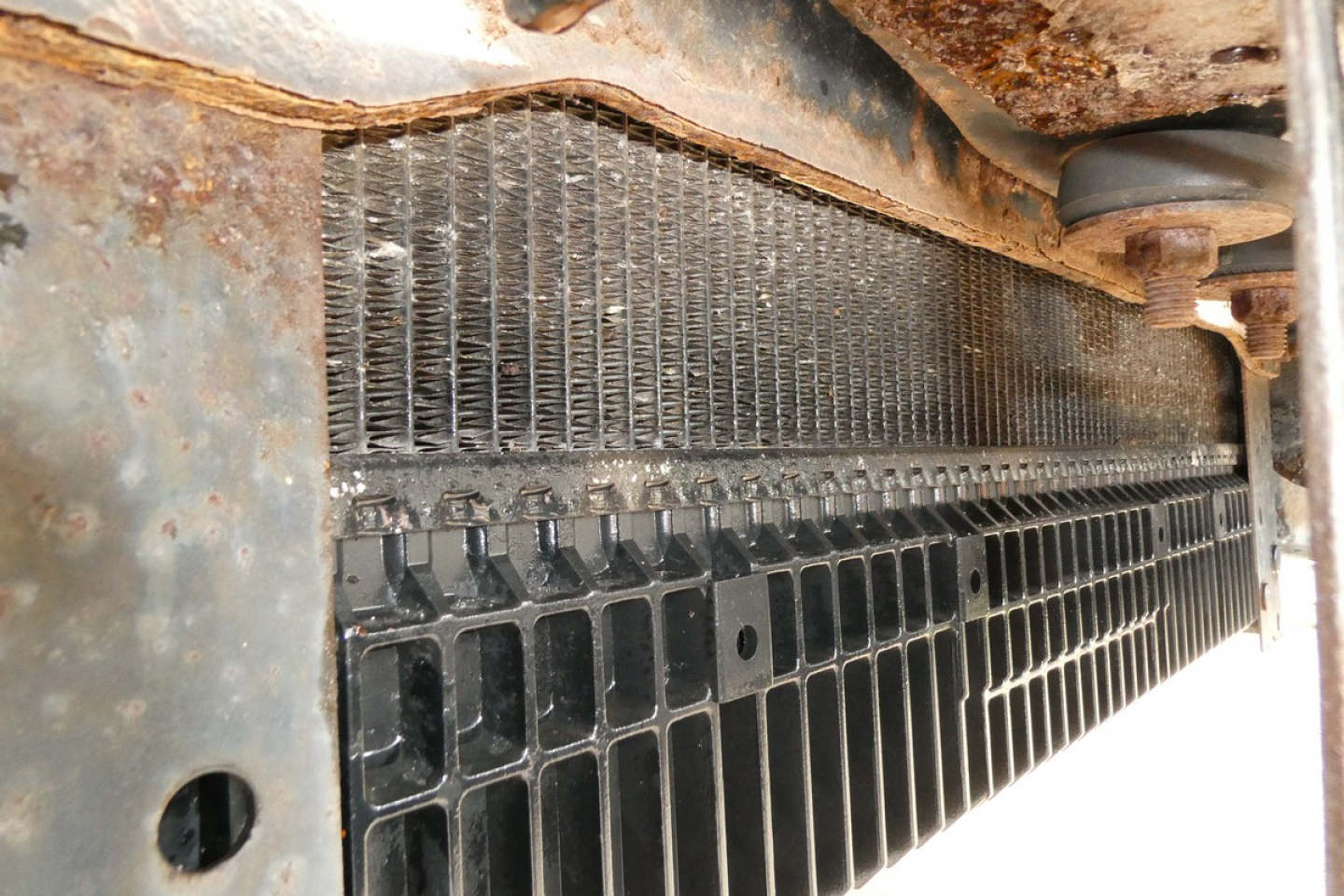 Freightliner M2-106 front grille area with radiator and grill visible, showing metal supports and mesh.