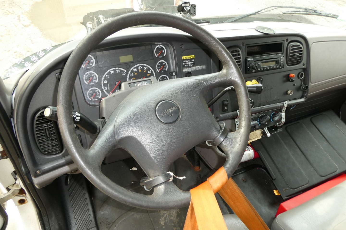 Truck cab interior showing steering wheel and instrument cluster of a Freightliner M2-106.