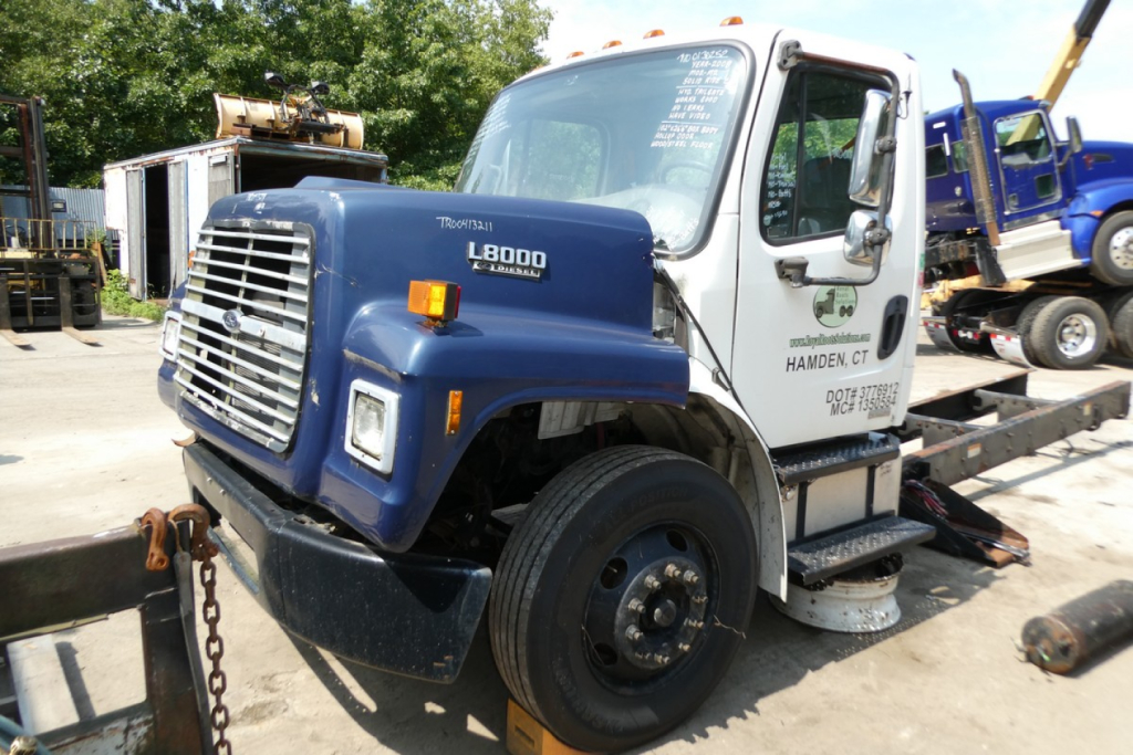 2008 Freightliner M2-106 cab over engine hood with L8000 diesel badge and front grille visible in a yard.