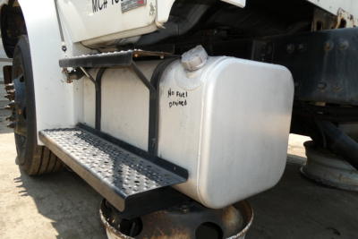 Truck fuel tank and step on a 2008 Freightliner M2-106 showing metal fuel tank with no fuel primed note and perforated step.