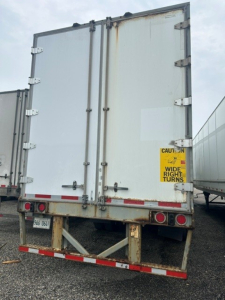 Back view of a 2009 Great Dane dry van trailer showing double doors with hinges, rear bumper, taillights, and caution sticker on door.