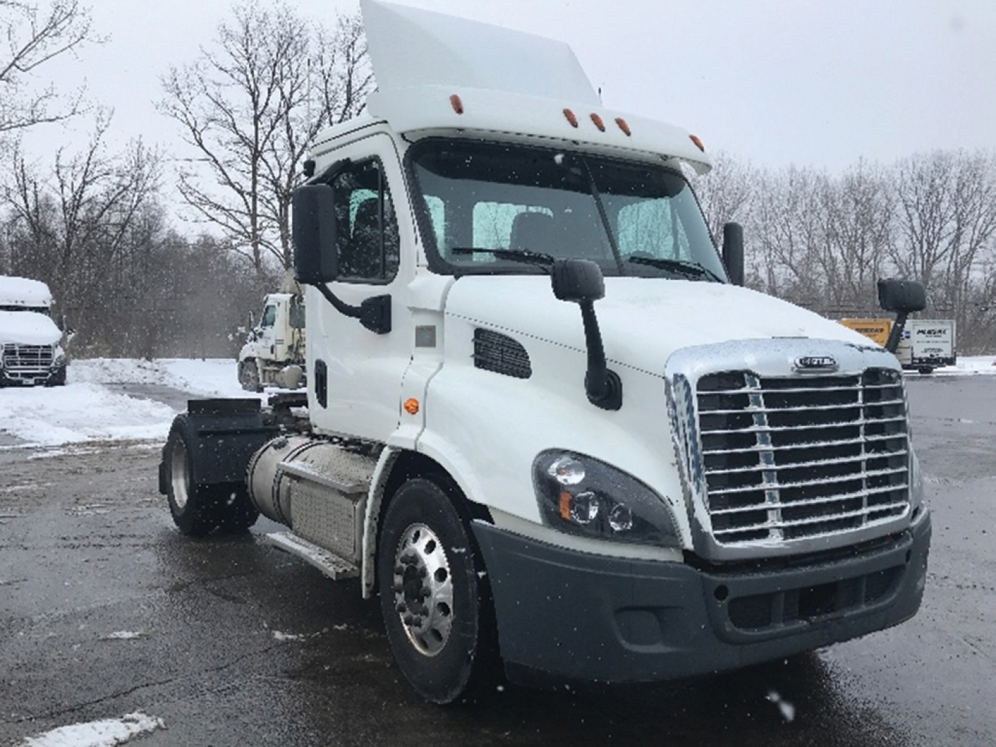 Freightliner Cascadia113 truck in a snowy lot showing cab and front grille.