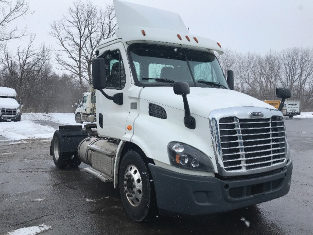 Freightliner Cascadia113 truck in a snowy lot showing cab and front grille.