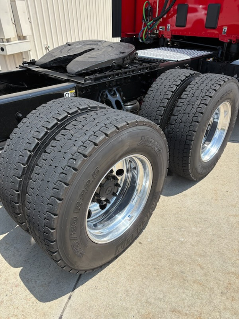 Kenworth T680 chassis rear showing dual rear wheels and tires, fifth wheel area, chrome rims, with visible suspension and frame components.